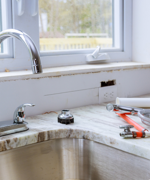 A kitchen sink with tools on the counter