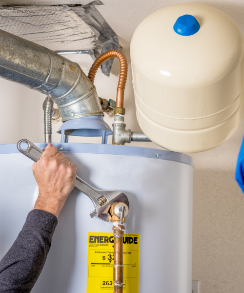 A man fixing a water heater with a wrench