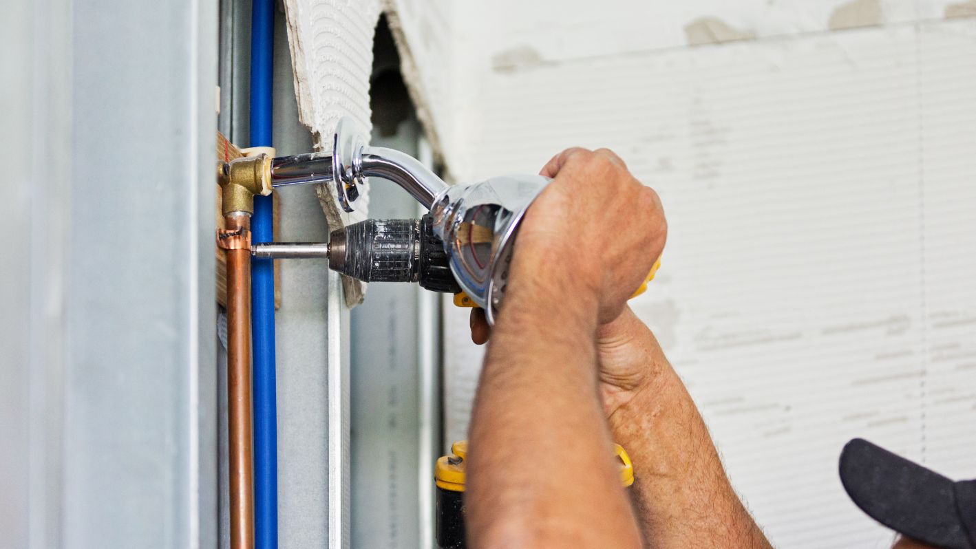 A man fixing a water heater on a wall